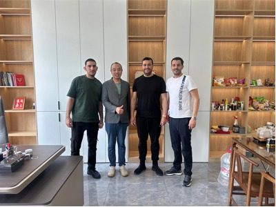 The owner of Yangbang Machinery poses for a photo with a customer in his office.