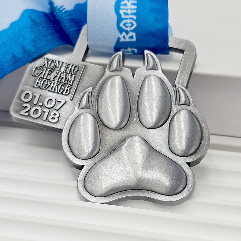 Frosted silver metal medal with bear paw design, commemorative event item, 3D paw print relief, outdoor sports collectible.