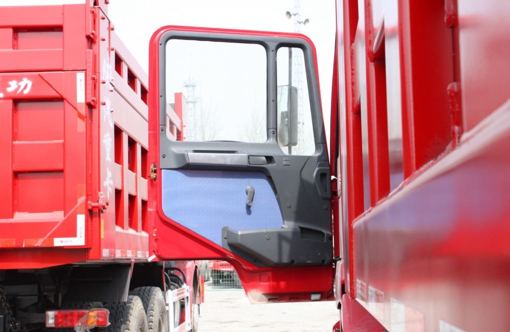 Shacman F2000 6x4 dump truck driver side door detail showing handle, cabin access, and reinforced construction Camião basculante Shacman F2000 6×4
