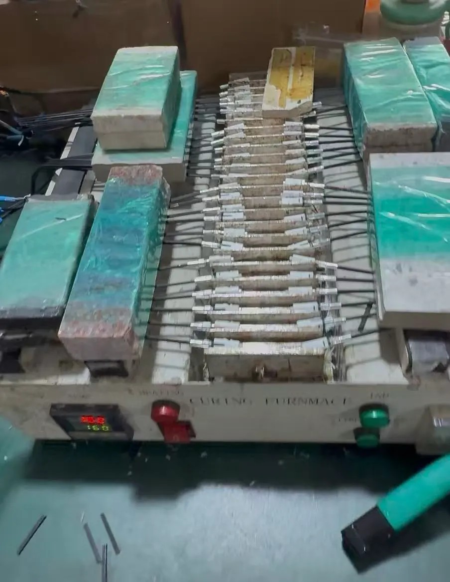 Drop cable connector assemblies held in an epoxy curing furnace at LinkFiber Drop cable connector assemblies held in an epoxy curing furnace at LinkFiber